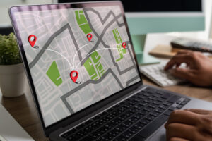 Frau telefoniert und nutzt GPS-Kartensoftware auf Laptop